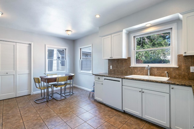 kitchen with a sink, white dishwasher, tasteful backsplash, tile patterned flooring, and baseboards
