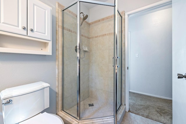 bathroom with a stall shower, toilet, tile patterned flooring, and baseboards