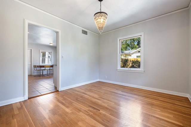 unfurnished room with a chandelier, light wood-type flooring, crown molding, and baseboards