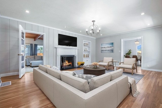 living area with crown molding, baseboards, recessed lighting, light wood-style floors, and a chandelier