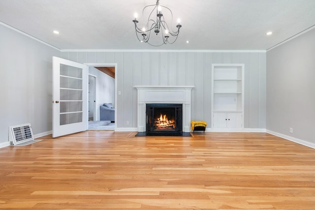 unfurnished living room with ornamental molding, french doors, built in shelves, a chandelier, and light wood-style flooring