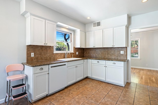 kitchen with a sink, white dishwasher, white cabinets, backsplash, and recessed lighting