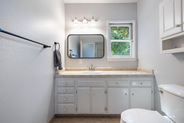 bathroom with toilet, vanity, and tile patterned floors