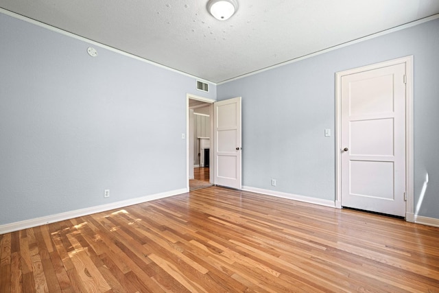 unfurnished room with light wood-style floors, baseboards, crown molding, and a textured ceiling