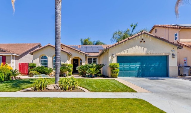 5179 E Lyell Ave, Fresno, CA 93727 - mediterranean / spanish house with solar panels, a garage, stucco siding, a front yard, and driveway