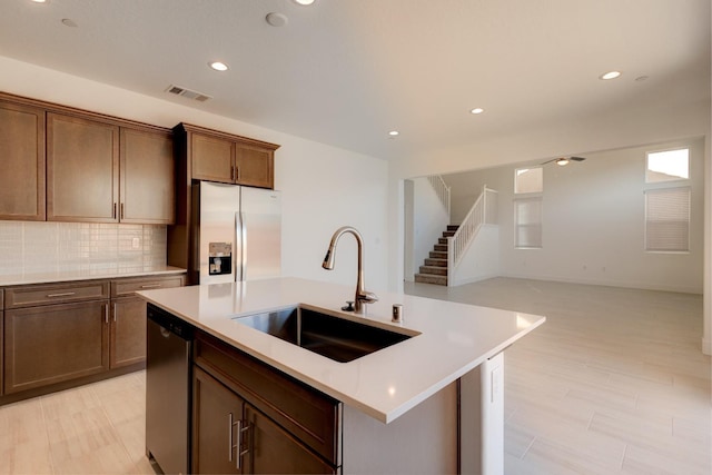 495 Thunder Rd S, Madera, CA 93636 - kitchen featuring appliances with stainless steel finishes, a sink, light countertops, decorative backsplash, and a kitchen island with sink