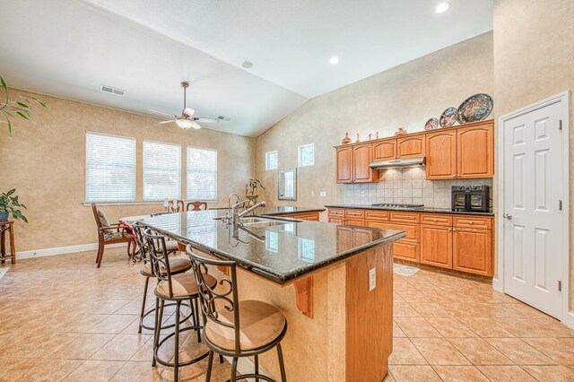 3251 Alamos Ave, Clovis, CA 93619 - kitchen with a sink, light tile patterned flooring, stainless steel gas stovetop, under cabinet range hood, and vaulted ceiling