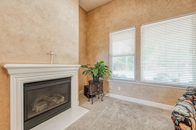 detailed view of carpet floors, a glass covered fireplace, and baseboards