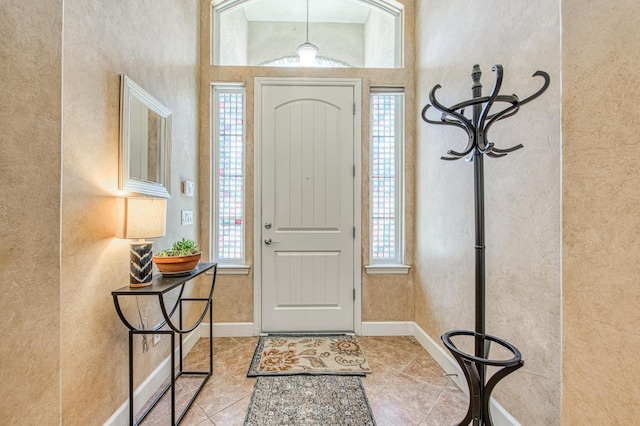 tiled foyer entrance featuring a textured wall and baseboards