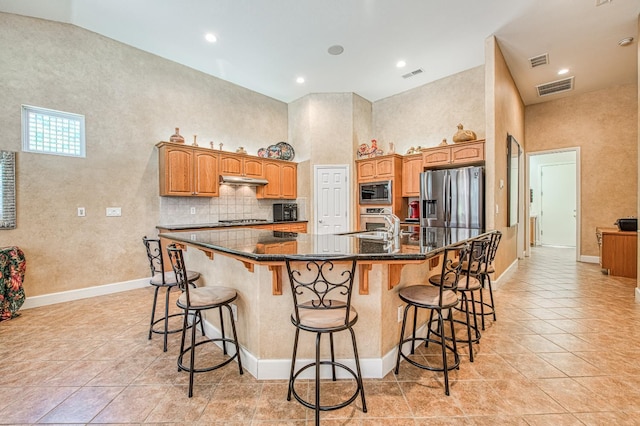 kitchen featuring stainless steel appliances, light tile patterned floors, a large island with sink, a breakfast bar, and recessed lighting