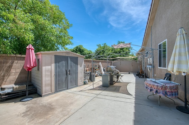 view of patio / terrace with a storage unit, a fenced backyard, an outbuilding, and area for grilling
