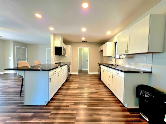 41549 Long Hollow Dr, Coarsegold, CA 93614 - kitchen with appliances with stainless steel finishes, dark countertops, a sink, a kitchen bar, and recessed lighting