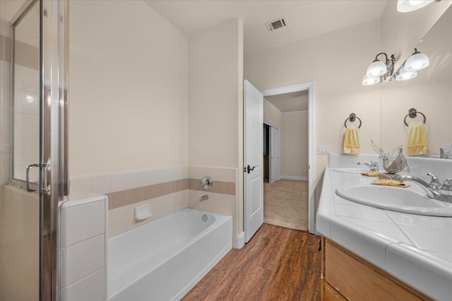 full bathroom with wood finished floors, a garden tub, double vanity, and a stall shower