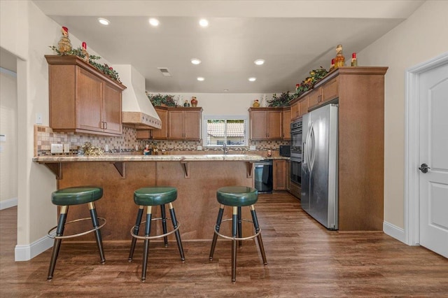 6458 N Warren Ave, Fresno, CA 93711 - kitchen featuring stainless steel appliances, dark wood-type flooring, decorative backsplash, a breakfast bar area, and a peninsula