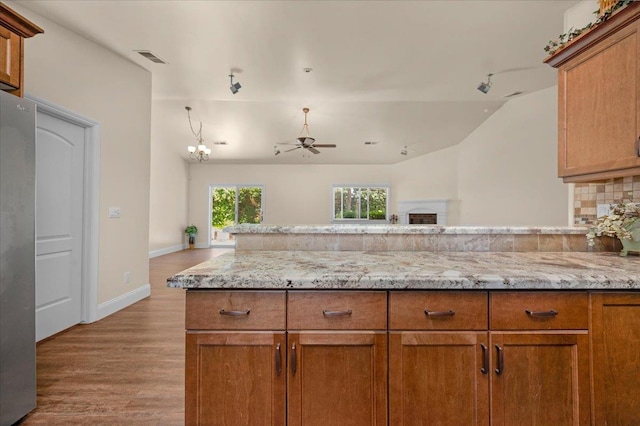 6458 N Warren Ave, Fresno, CA 93711 - kitchen featuring wood finished floors, freestanding refrigerator, a ceiling fan, light stone countertops, and brown cabinetry