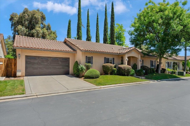 mediterranean / spanish house with an attached garage, concrete driveway, a tiled roof, and stucco siding