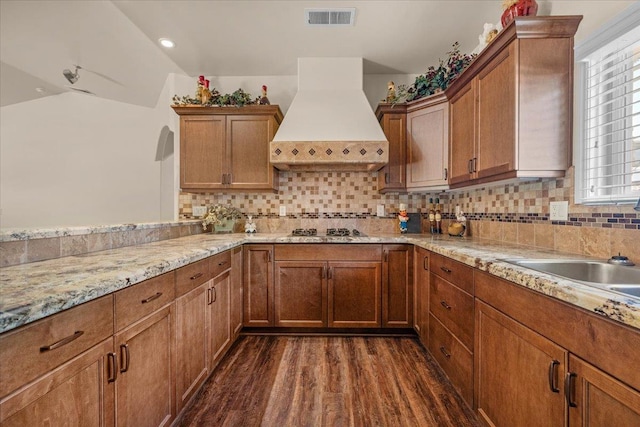 6458 N Warren Ave, Fresno, CA 93711 - kitchen featuring custom range hood, dark wood finished floors, stainless steel gas stovetop, decorative backsplash, and brown cabinetry