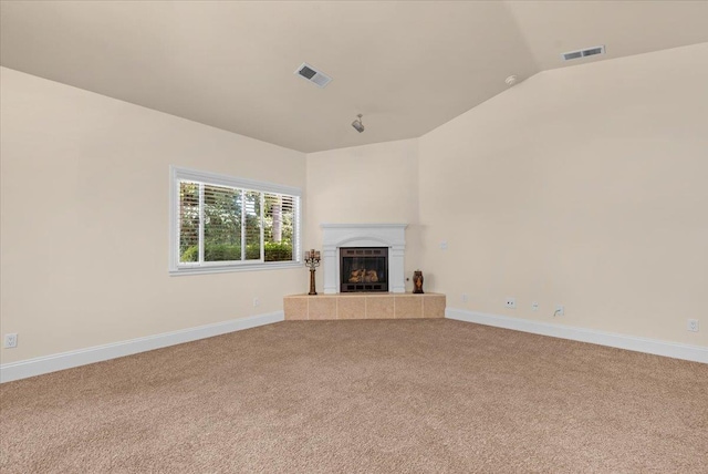 unfurnished living room with carpet, vaulted ceiling, a tiled fireplace, and baseboards
