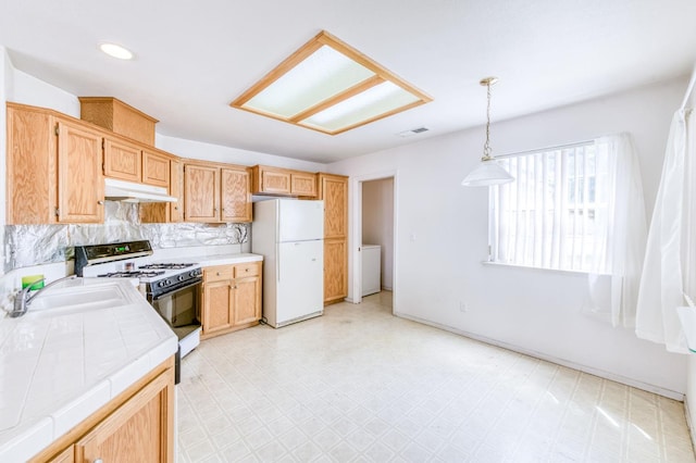 2670 N Katy Ave, Fresno, CA 93722 - kitchen featuring freestanding refrigerator, tile countertops, gas range oven, under cabinet range hood, and light floors