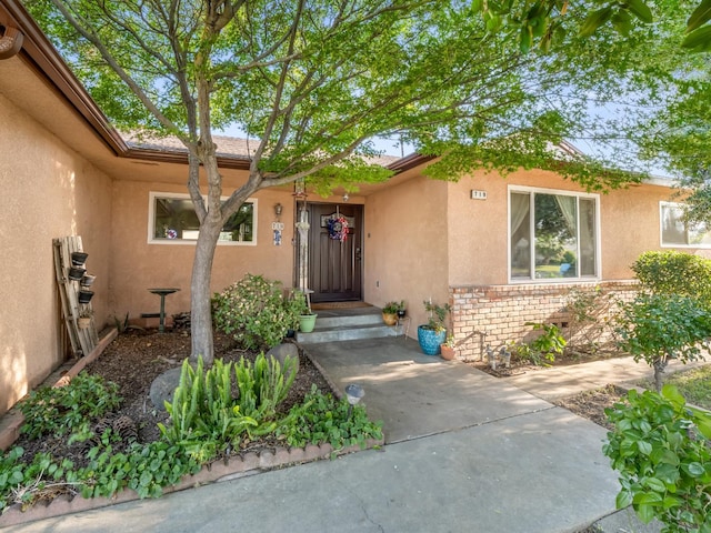 property entrance with stucco siding and brick siding