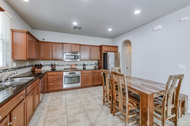 3507 Significant Way, Clovis, CA 93619 - kitchen with appliances with stainless steel finishes, a sink, arched walkways, decorative backsplash, and brown cabinets