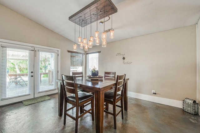 dining area with concrete floors, french doors, baseboards, lofted ceiling, and a chandelier