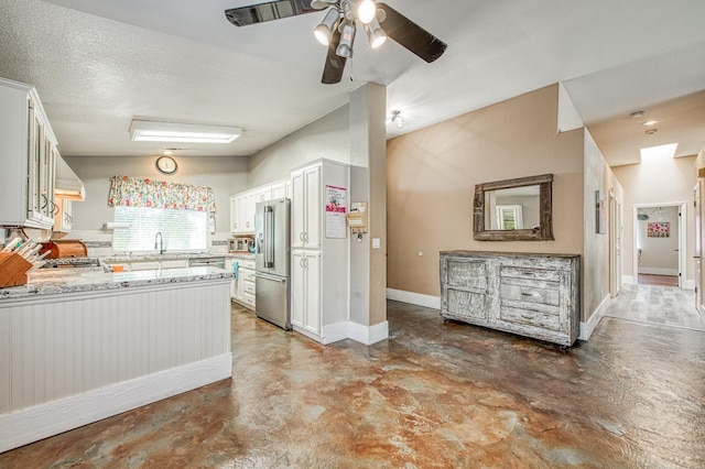 kitchen with appliances with stainless steel finishes, concrete flooring, a ceiling fan, and white cabinets