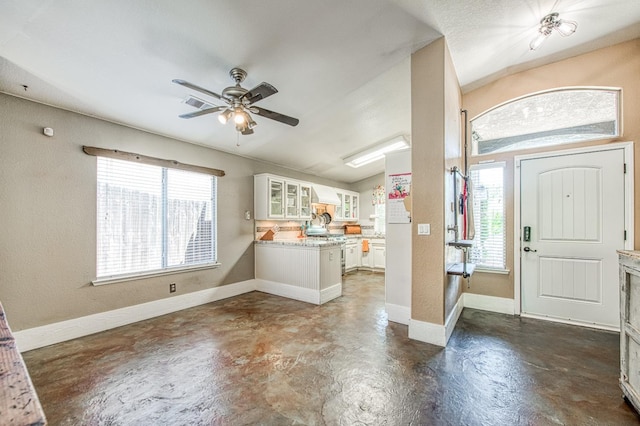 entrance foyer featuring concrete floors, healthy amount of natural light, ceiling fan, and baseboards