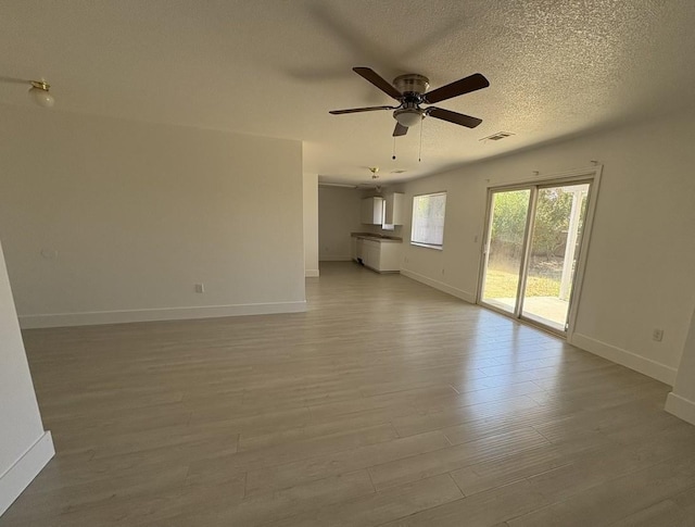 1073 Hickory St, Lindsay, CA 93247 - unfurnished living room with light wood-type flooring, a ceiling fan, baseboards, and a textured ceiling