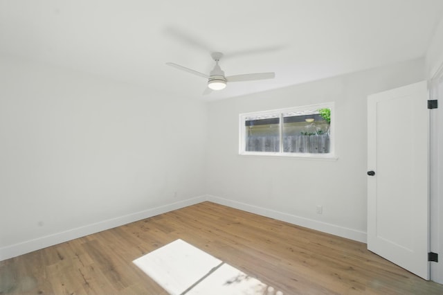 spare room with baseboards, wood finished floors, and a ceiling fan