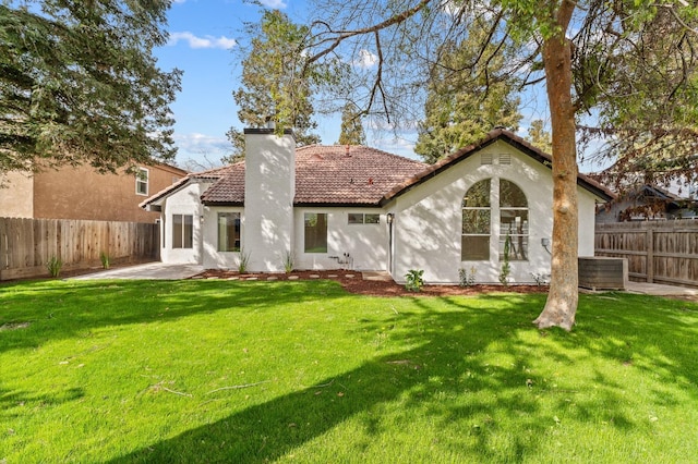 rear view of house featuring a tile roof, stucco siding, a chimney, and a patio