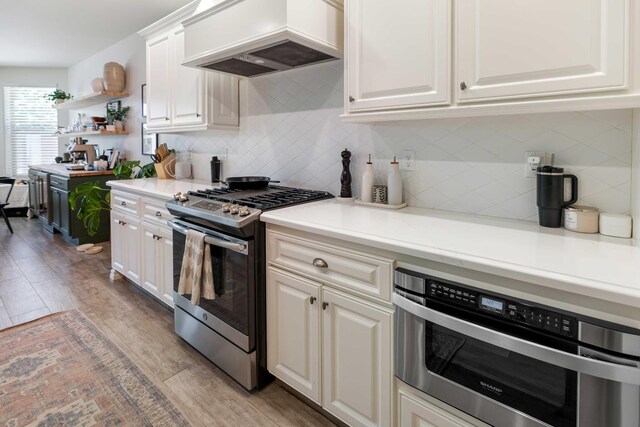 2506 20th Ave, Kingsburg, CA 93631 - kitchen with stainless steel appliances, custom exhaust hood, light countertops, light wood finished floors, and white cabinets