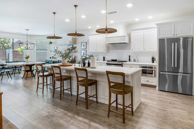 2506 20th Ave, Kingsburg, CA 93631 - kitchen featuring appliances with stainless steel finishes, custom exhaust hood, an island with sink, light countertops, and a breakfast bar area
