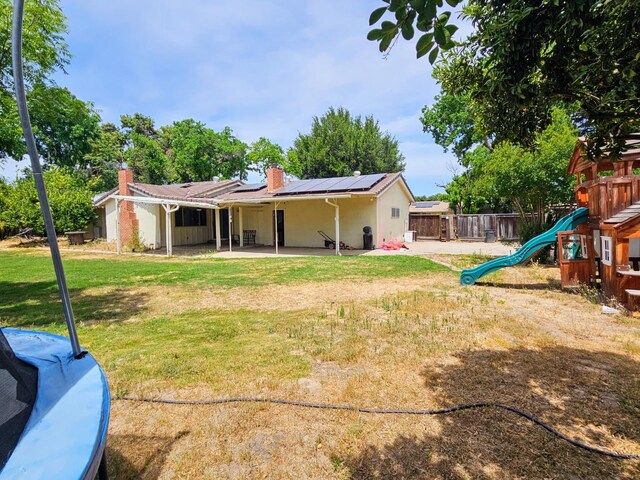5850 E Parkside Dr, Fresno, CA 93727 - back of house featuring a playground, a patio area, roof mounted solar panels, a chimney, and metal roof