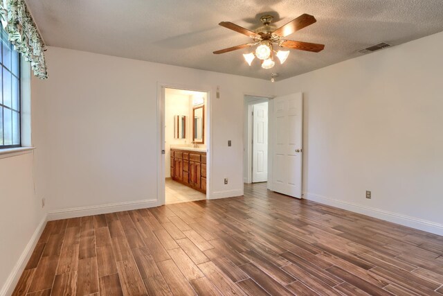 42177 Lone Olive Ln, Ahwahnee, CA 93601 - unfurnished bedroom featuring wood finished floors, baseboards, a sink, ensuite bathroom, and a textured ceiling