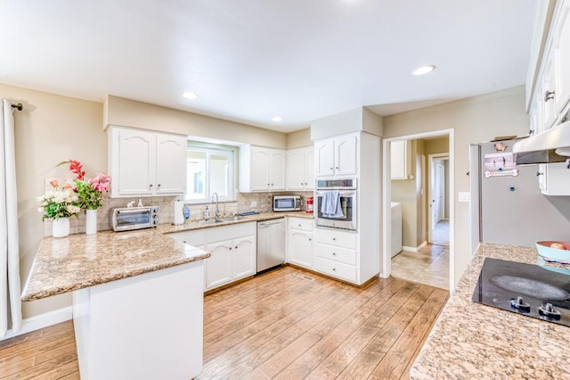 kitchen featuring stainless steel appliances, a sink, a peninsula, light wood-type flooring, and recessed lighting