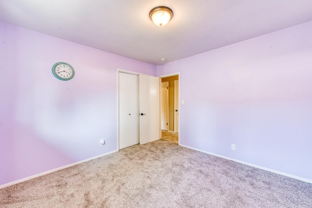 unfurnished bedroom featuring carpet floors, a closet, and baseboards
