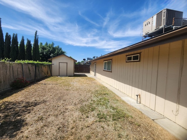 fenced backyard featuring a storage shed, an outdoor structure, and central AC unit