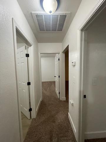 hallway featuring carpet and baseboards