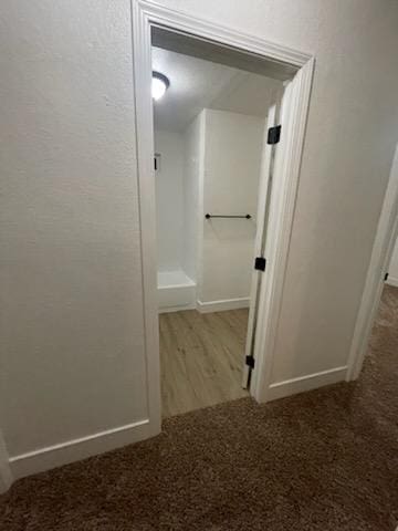 hallway featuring carpet flooring, baseboards, and wood finished floors