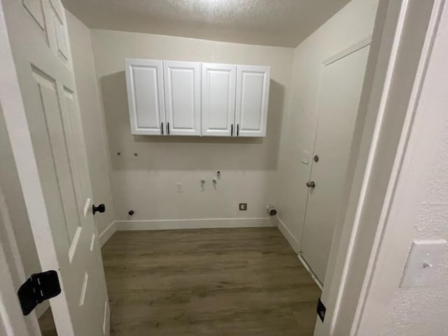 laundry room with hookup for a gas dryer, cabinet space, wood finished floors, baseboards, and a textured ceiling