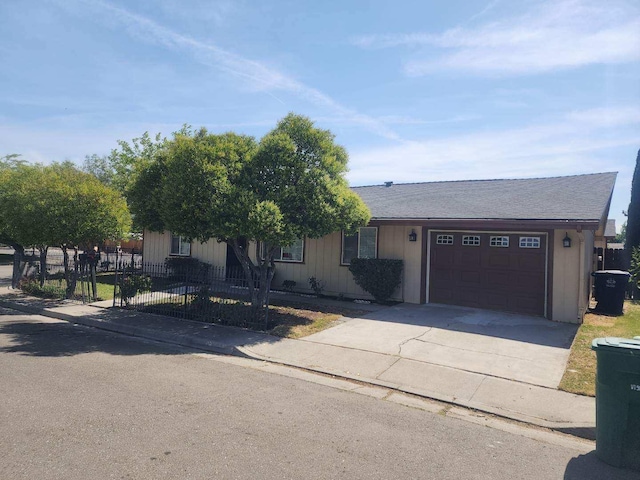 view of front facade featuring an attached garage, driveway, and fence