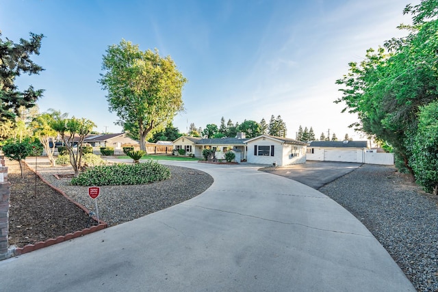 ranch-style home featuring curved driveway and a detached garage