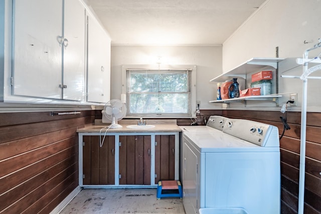 washroom with separate washer and dryer, cabinet space, and wooden walls