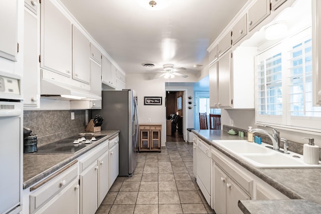 kitchen featuring a sink, white appliances, white cabinets, ceiling fan, and decorative backsplash