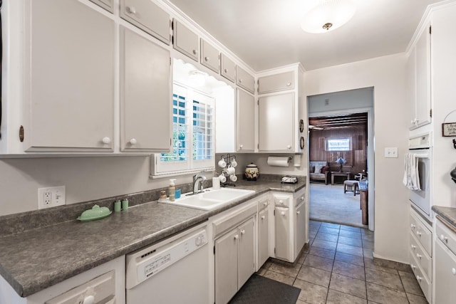 kitchen with white appliances, a sink, plenty of natural light, and dark countertops