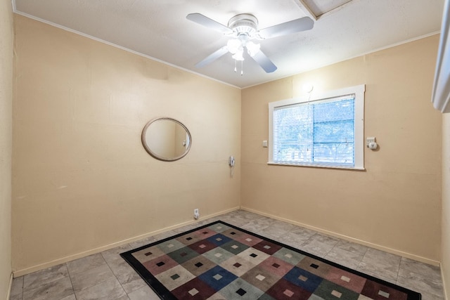 spare room featuring a ceiling fan, baseboards, ornamental molding, and light tile patterned floors
