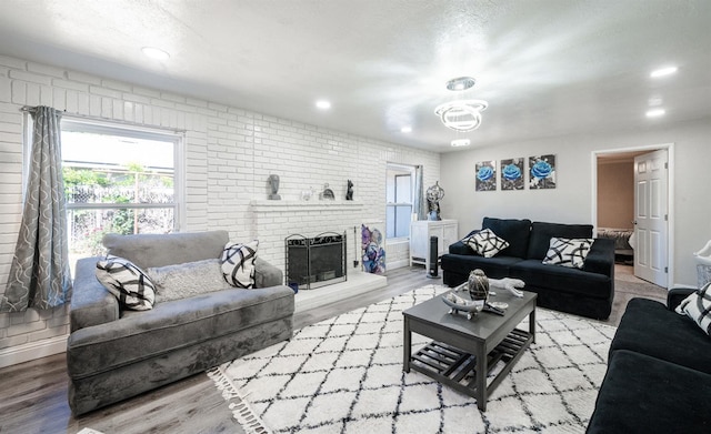 living room featuring healthy amount of natural light, wood finished floors, recessed lighting, a fireplace, and baseboards
