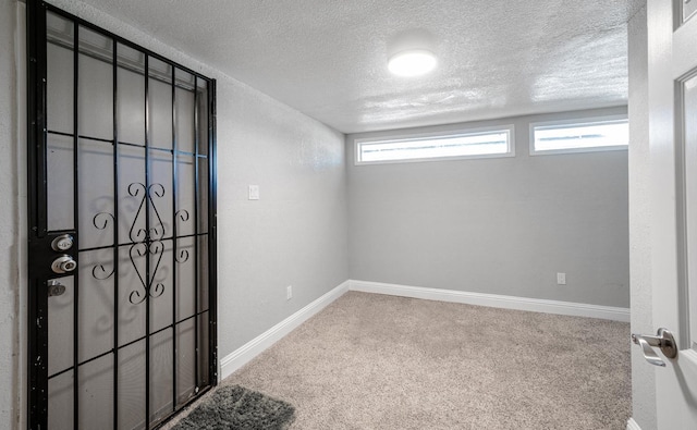 unfurnished room featuring carpet flooring, a textured ceiling, and baseboards