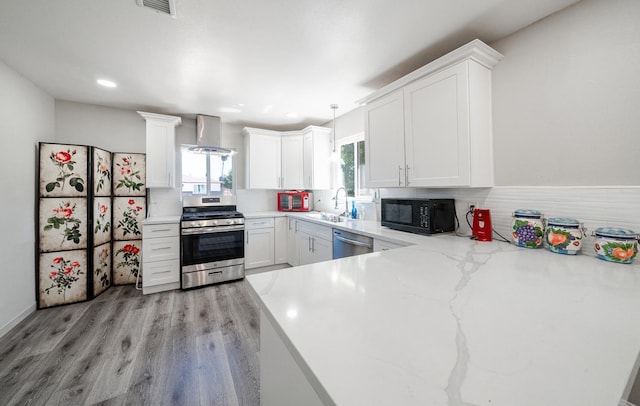 kitchen with stainless steel appliances, wall chimney range hood, a sink, plenty of natural light, and recessed lighting